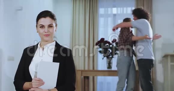 在镜头前漂亮的房子经纪人看着镜头拿着她的平板电脑在背景上快乐和快乐视频的预览图