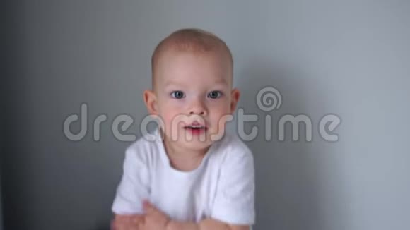 穿白色T恤的两岁蓝眼睛男孩的肖像可爱的男婴看着摄像机拍手视频的预览图