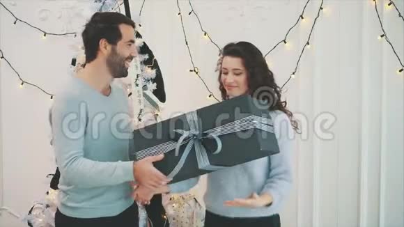 可爱的古怪女孩从男朋友那里得到了一份圣诞礼物手里拿着一个盒子靠近耳朵颤抖着听着什么是什么视频的预览图