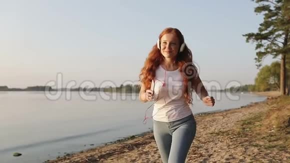 带着红色卷发的年轻微笑女人做晚间体育锻炼视频的预览图