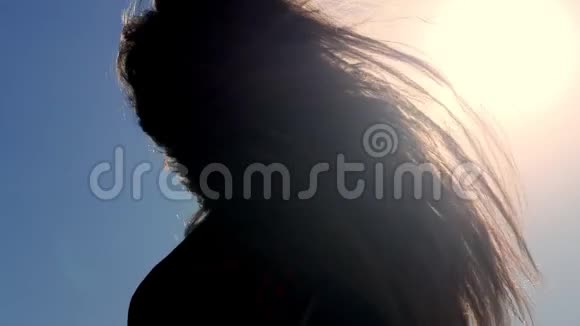 肖像少年女孩在阳光下跳舞的黑暗剪影她的头发在风中飘扬视频的预览图