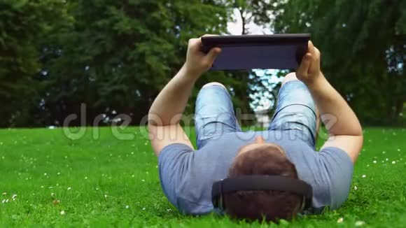男人躺在公园里用平板电脑视频的预览图