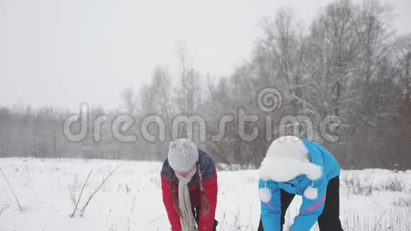 家庭在冬季公园玩圣诞假期快乐的母亲和女儿吐雪雪落和闪闪发光视频的预览图