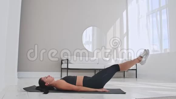 在家训练女运动员适合女性运动员在白色公寓里躺在地板上做脚趾接触单臂运动视频的预览图