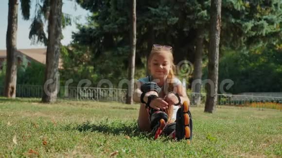 坐在草地上的小女孩穿上了她的旱冰鞋视频的预览图