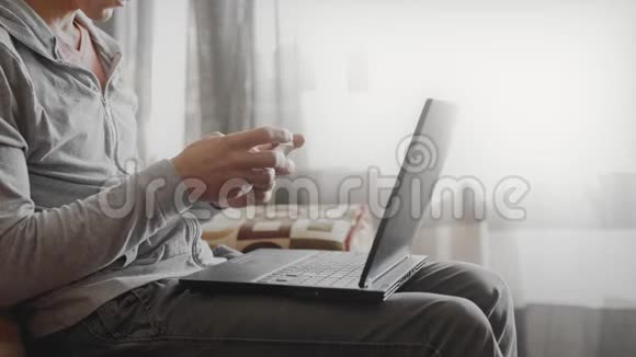 男人坐在沙发上用手机和笔记本电脑视频的预览图