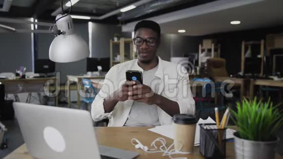 美国黑人年轻人在办公室里使用手机和笔记本电脑视频的预览图