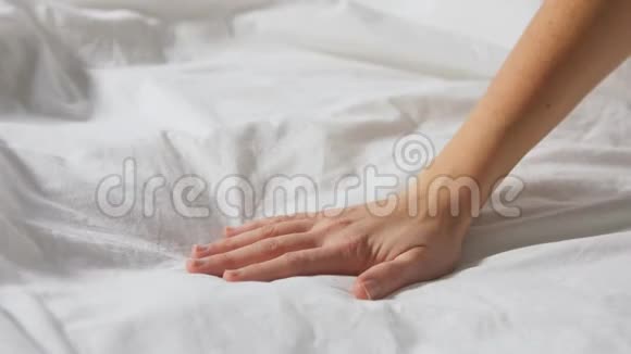 女人用手摸着被毯子覆盖的床视频的预览图