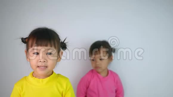 一个快乐微笑的亚洲儿童女孩和她的姐姐穆迪的肖像背后孤立的白色背景视频的预览图