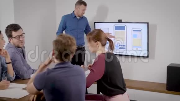 在办公室报到一个人以自己的方式为同事做演讲商业幻灯片显示在电视上视频的预览图