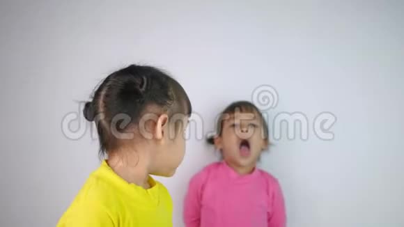一个快乐微笑的亚洲儿童女孩和她的姐姐穆迪的肖像背后孤立的白色背景视频的预览图