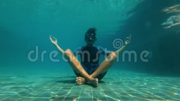 慢动作水下拍摄一个年轻人在瑜伽姿势冥想游泳池底部他被视频的预览图
