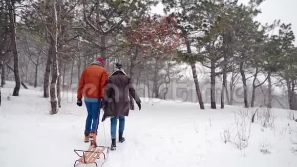 可爱的一对夫妇在下雪的冬天散步拉雪橇有女朋友的人会在下雪的时候滑雪女人要去视频的预览图