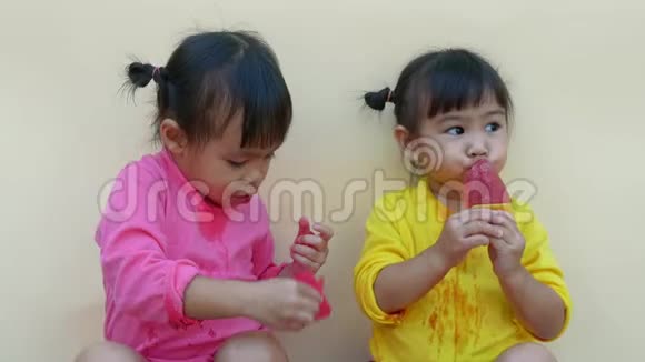 一个快乐微笑的兄弟姐妹女孩的肖像享受吃冰淇淋隔离在白色背景视频的预览图