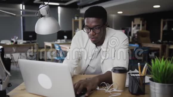 美国黑人年轻人在笔记本电脑上工作在办公室使用电话视频的预览图