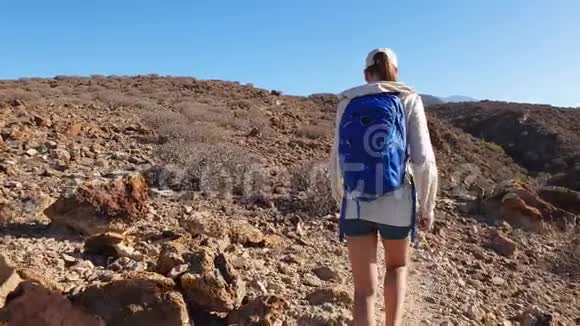 年轻女子在火山岛荒山徒步旅行的慢动作录像视频的预览图