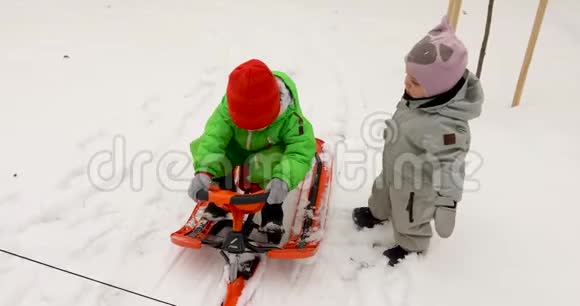 穿着冬装的可爱的孩子们一起坐着雪橇视频的预览图