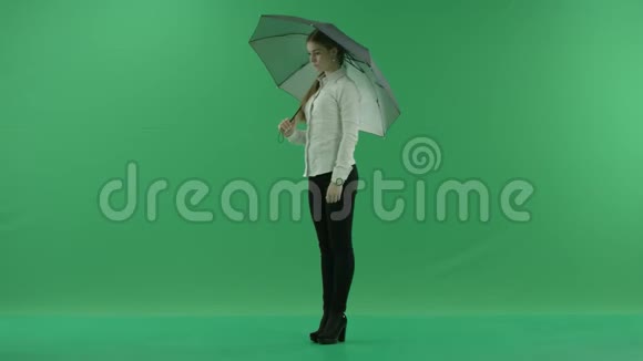 一个体贴的女人正在等待并检查她站在左边的绿色屏幕上的伞她穿着正式的衣服视频的预览图