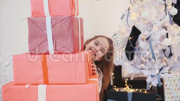可爱的孩子为她的朋友和家人准备了圣诞礼物正从一堆红色礼品盒后面偷看视频的预览图