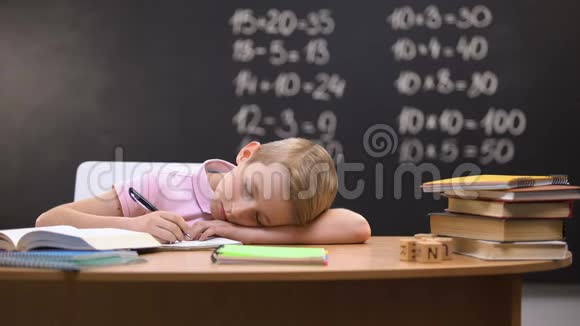 疲惫的小学生在桌子上打盹在准备作业时睡着了视频的预览图