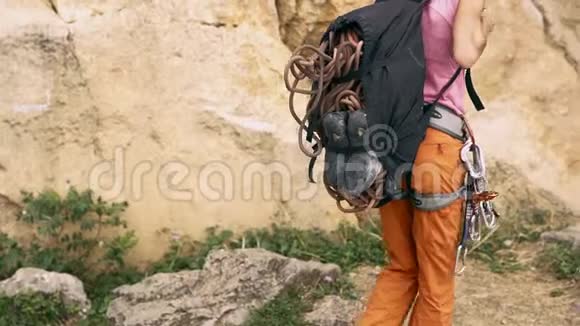 攀岩的细节后景妇女带着背包用于攀爬设备步行到悬崖并脱下他的背包视频的预览图