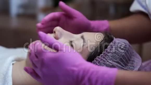 美容师在美容院给脸部和按摩妇女涂奶油视频的预览图
