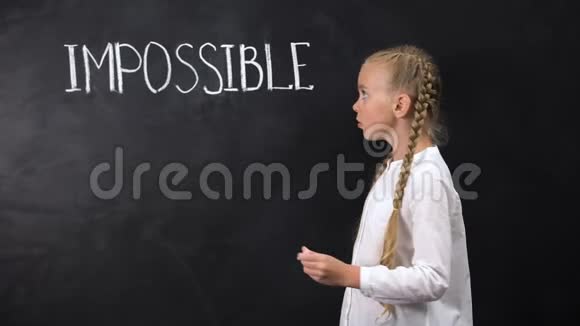 聪明的女孩站在黑板旁边在单词中跨越IMPOSIBLE动机视频的预览图