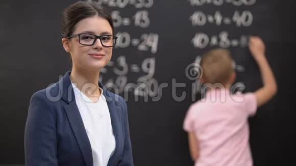 年轻的女教师寻找相机学生解决数学练习工作视频的预览图