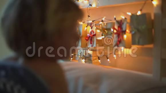 一个小男孩在床上醒来时的慢镜头伴随着圣诞灯的灯光照亮了他的到来日历视频的预览图