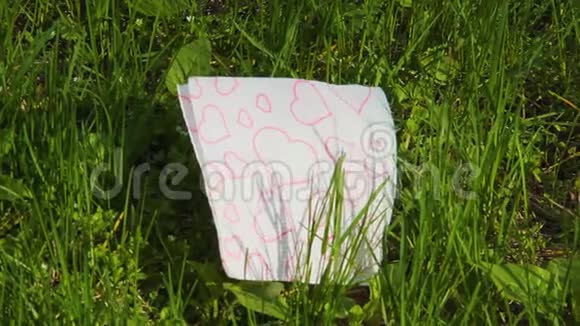红心的白纸巾纸轮廓躺在绿草上视频的预览图