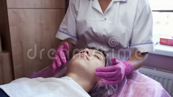 美容师在美容院给脸部和按摩妇女涂奶油视频的预览图