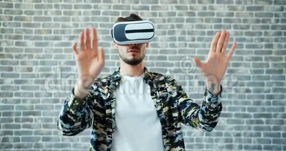使用虚拟现实眼镜移动双手在砖背景上的人画像视频的预览图