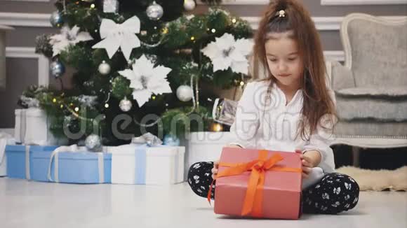 轻4k视频可爱的孩子坐在手中的礼物就像一个小侏儒在圣诞节装饰的房间视频的预览图