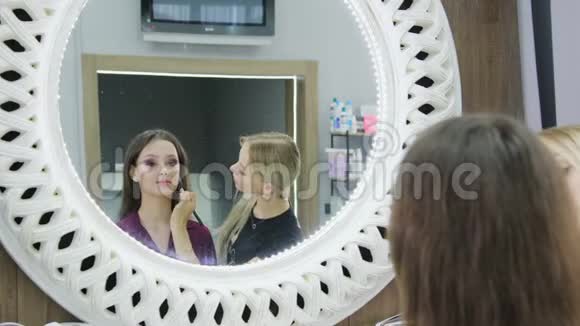 化妆师女站着在美容院做化妆可爱的美女视频的预览图