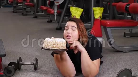 缺乏意志力饮食健身医疗保健肥胖的年轻女性在健身房里与蛋糕欲望作斗争的肖像体育运动视频的预览图