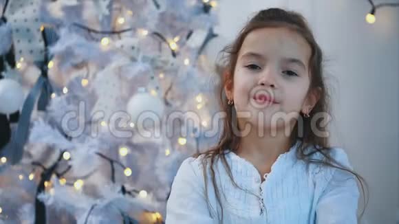 特写4k视频微笑的女孩小雪公主靠近圣诞树白色背景延伸两个假视频的预览图