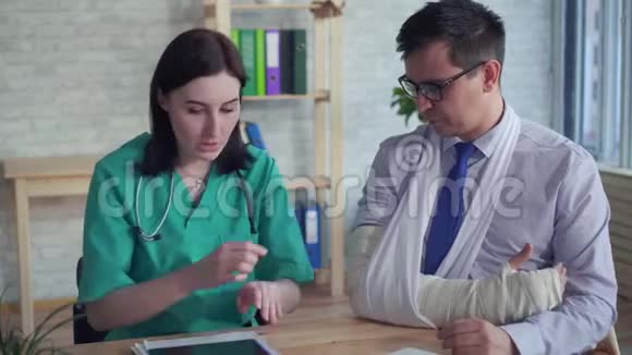 一位手里拿着x光的女医生与一个手臂骨折的病人沟通视频的预览图