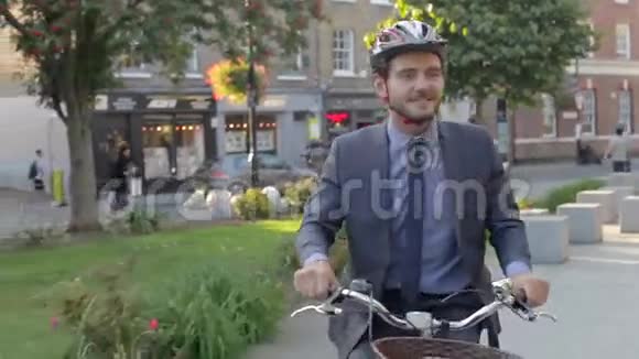 商人骑自行车穿过城市公园视频的预览图