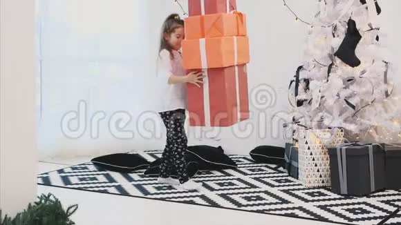 关爱的孩子带着一堆礼物盒送给她的朋友和家人圣诞树视频的预览图