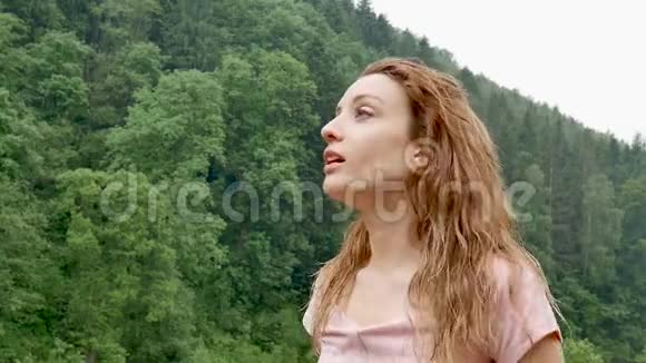 接近性感的年轻女人金发碧眼穿着粉红色的连衣裙在寒冷的夏雨中在户外呼吸视频的预览图