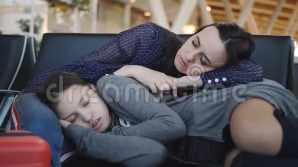 一名女子带着一个十几岁的女儿在机场休息室睡觉因为精疲力竭航班的取消视频的预览图