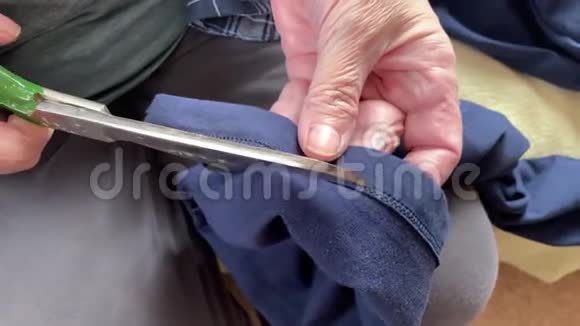 一位老年妇女奶奶用大剪刀剪布以便缝制双手合拢视频的预览图