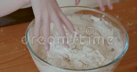 幼儿用手揉搓和混合面包面团放入玻璃搅拌碗中当她做面团的时候她的手特写视频的预览图