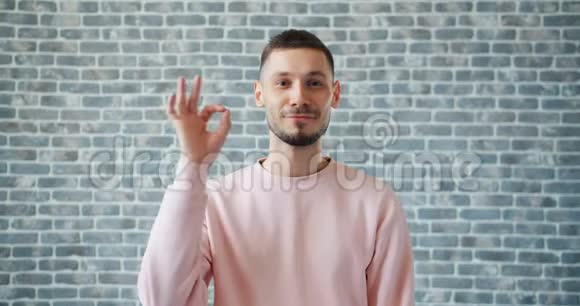 在砖墙背景上展现OK手势的欢快男人画像视频的预览图
