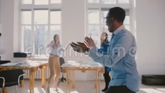 兴奋快乐的非裔美国商人做有趣疯狂的庆祝舞蹈与同事分享成功慢动作视频的预览图