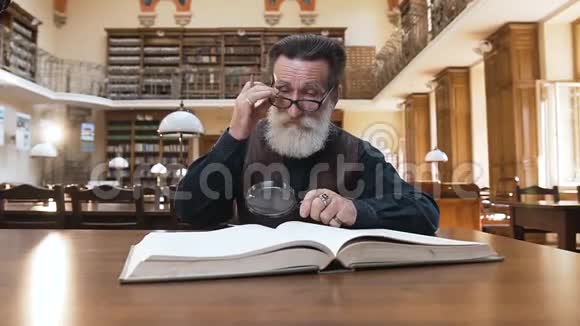 图书馆里书的时候一个聪明的大胡子老人摘下眼镜揉眼睛视频的预览图