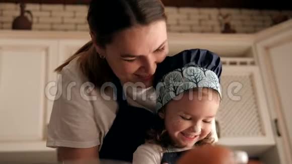 一位幸福的母亲和她的小女儿在家厨房的肖像视频的预览图