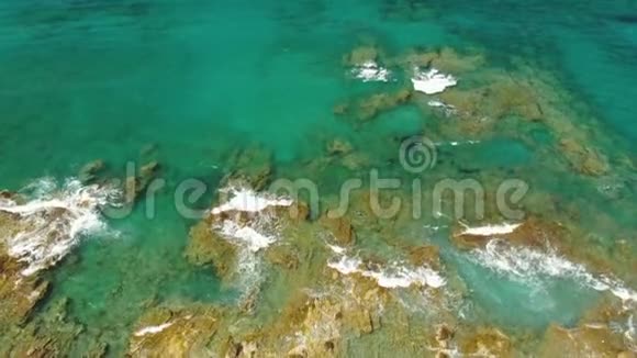 带石头和绿松石海波的悬崖海岸线的鸟瞰图垂直无人机视频的预览图