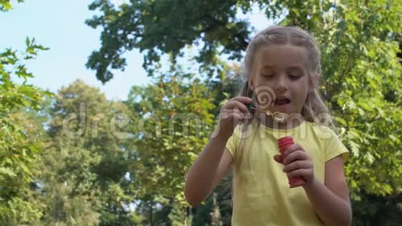 可爱的白种人女孩在公园里吹肥皂泡孩子们在户外玩得很开心视频的预览图