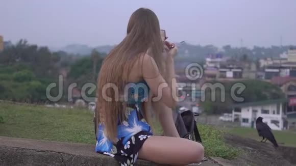 长发女人金发穿着裙子坐在草地上自己化妆视频的预览图